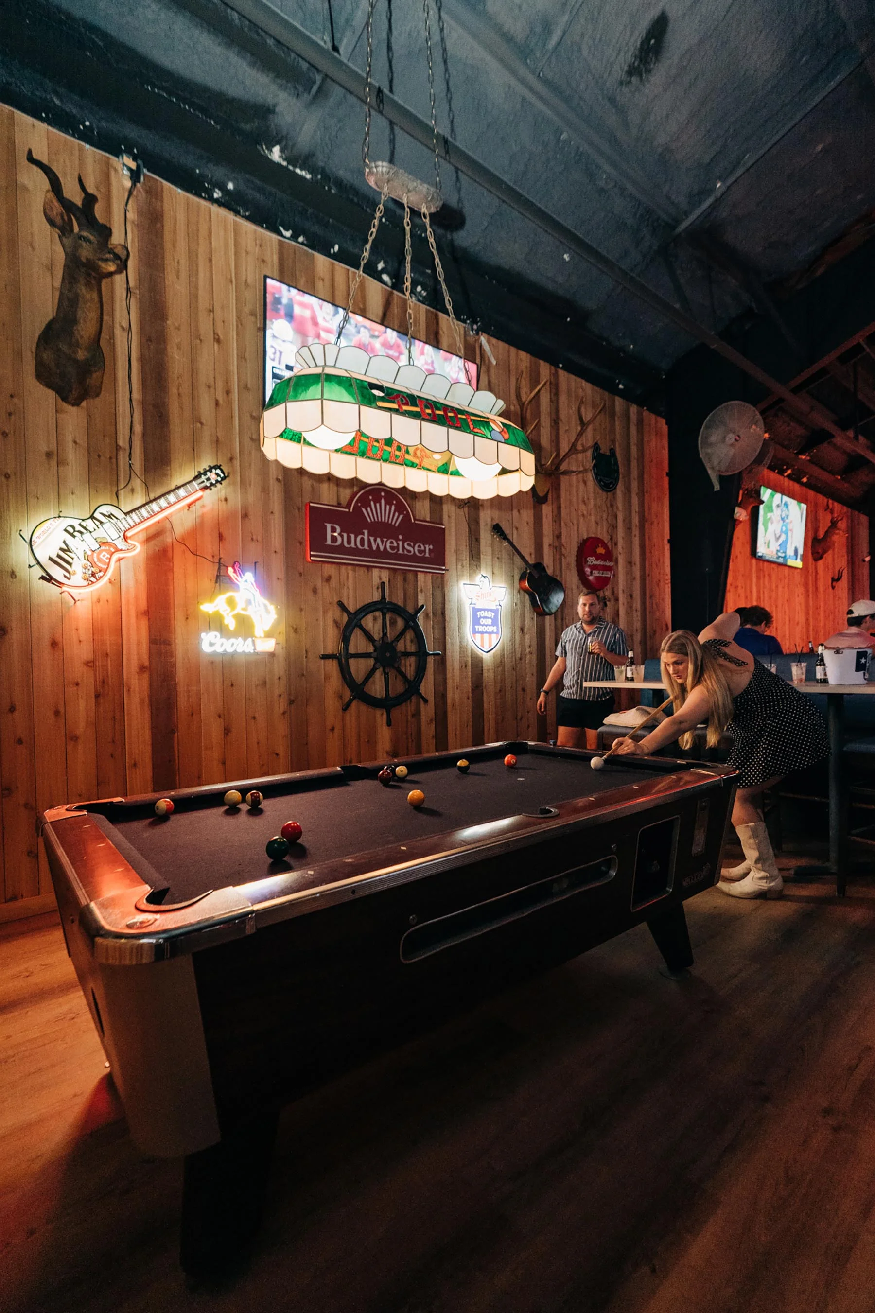 The pool table in the wood-panelled room at Cattlemen's Country Club, neon signs and mounted trophies on the walls