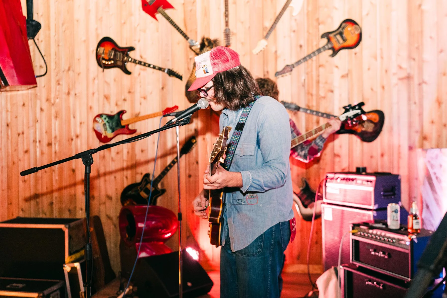 A guitarist performing at Cattlemen's Country Club, guitars mounted across the wood-panelled wall behind the stage