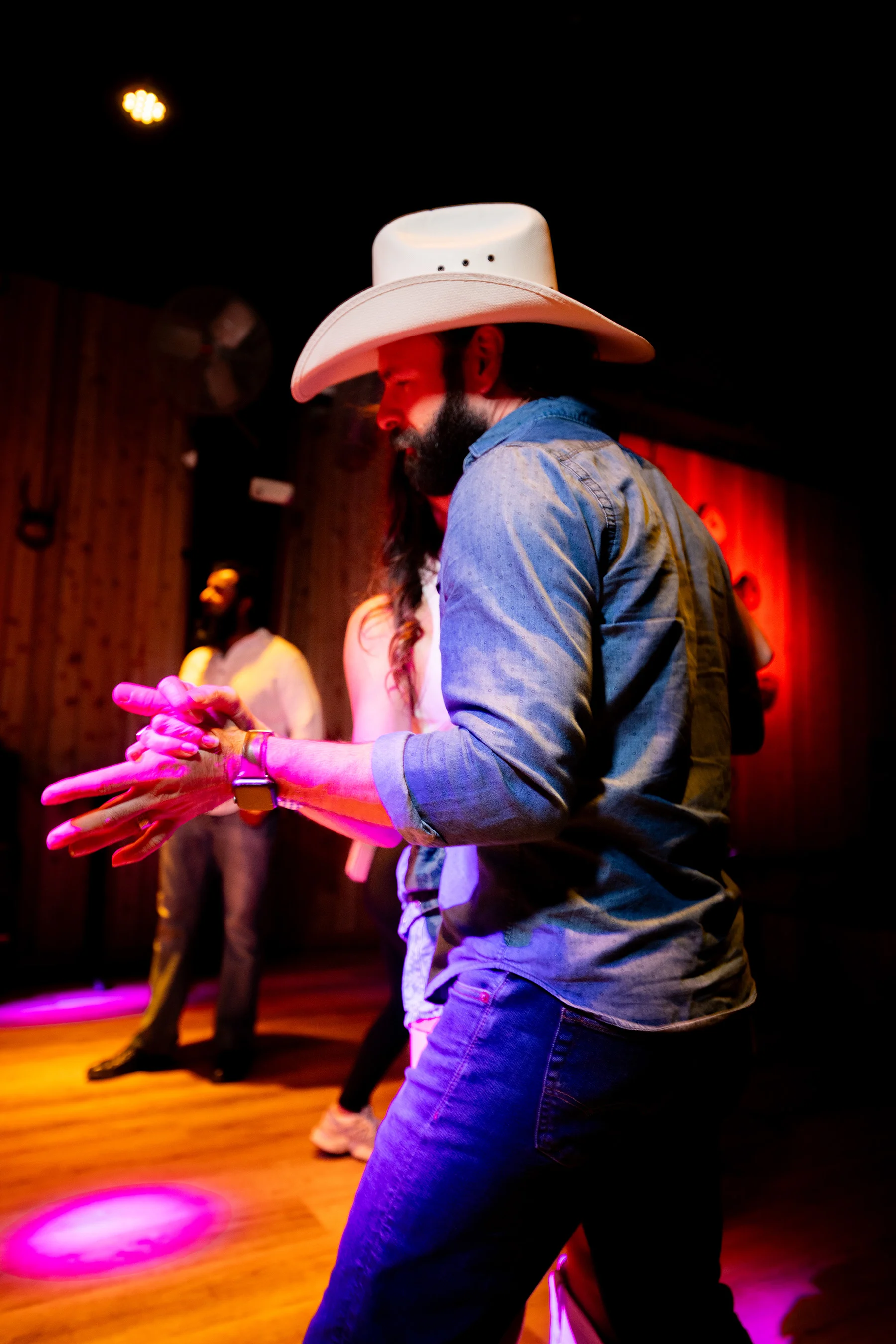 A dancer in a white cowboy hat mid-turn on the floor at Cattlemen's Country Club