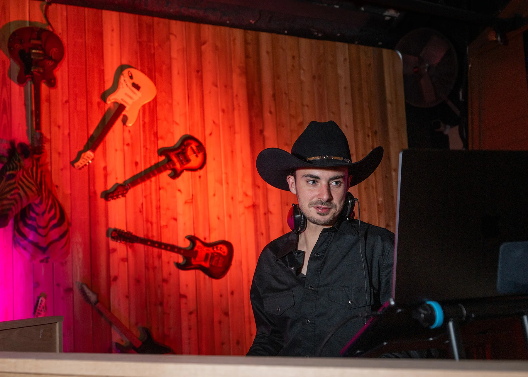 The booth at Cattlemen's Country Club under red light, guitars mounted on the wall behind