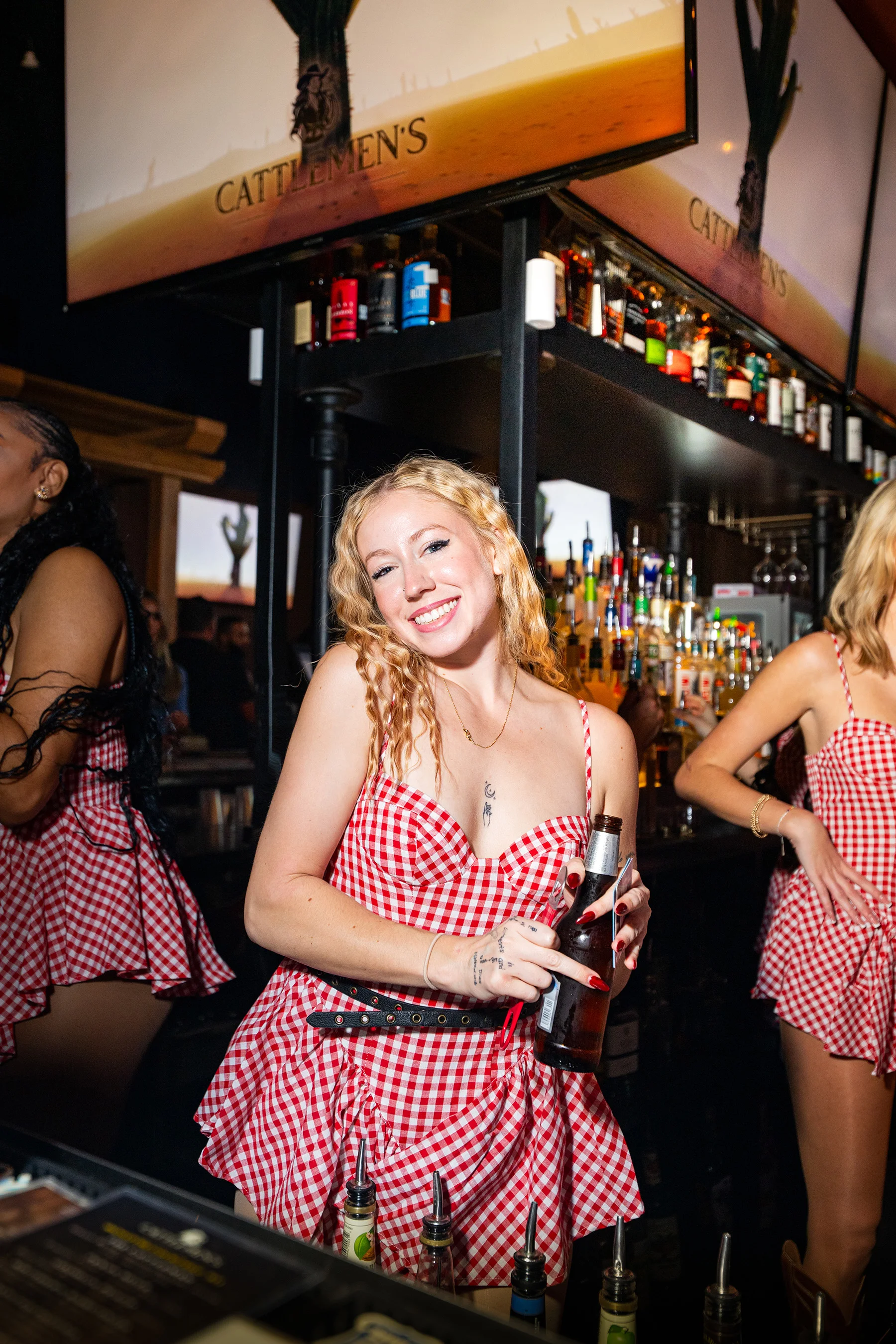 Bottles lined along the back bar at Cattlemen's Country Club, staff serving