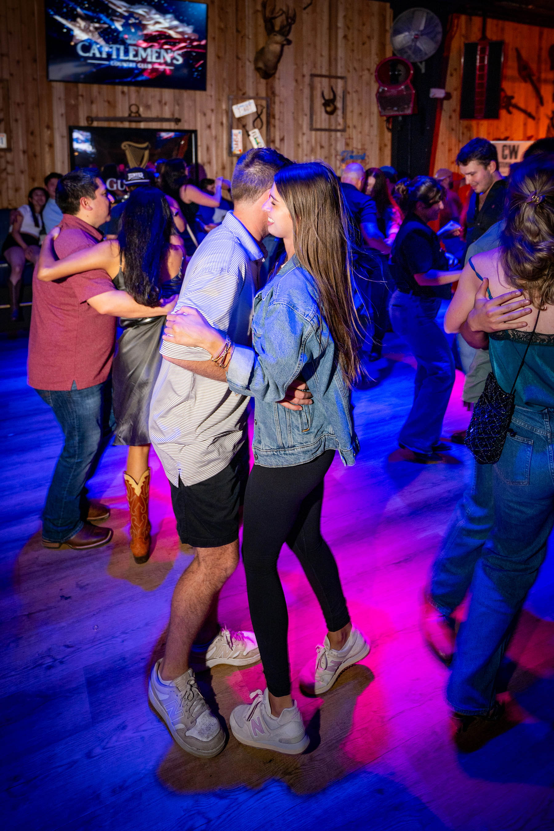Couples dancing together across the floor at Cattlemen's Country Club under purple light